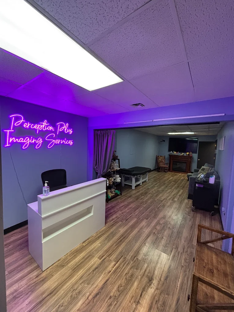 The studio reception desk, lit by the purple Perception Plus Imaging Services neon sign.